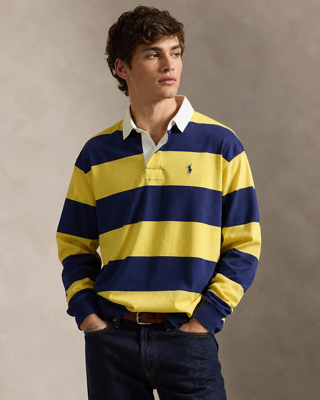 Model wearing a yellow and navy striped rugby shirt with denim